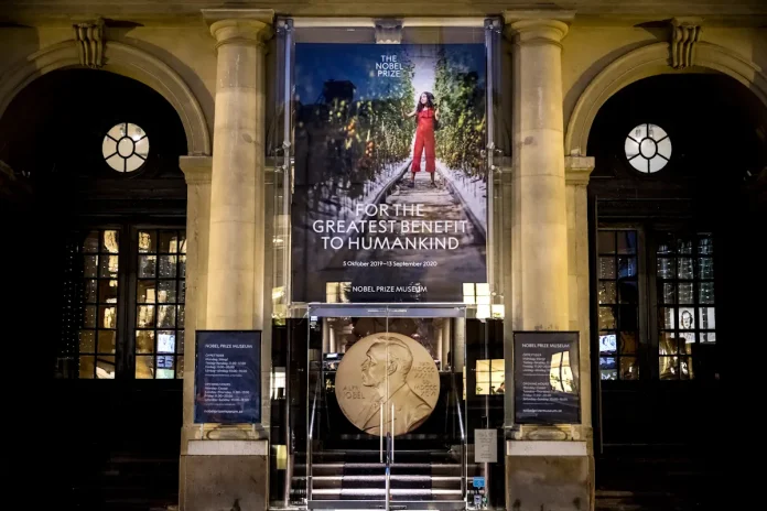 The Nobel Prize Museum main entrance with gold medal and the banner for an earlier thematic exhibition. Photo: Alexander Mahmoud © Nobel Prize Outreach